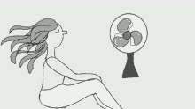 a woman is sitting in front of a fan with her hair blowing in the wind .