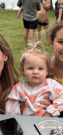 a woman is holding a little girl in her arms while sitting at a table .