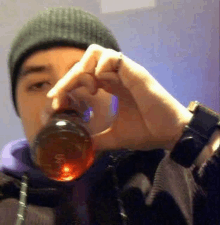 a man wearing a beanie is holding a glass of beer in his hand .