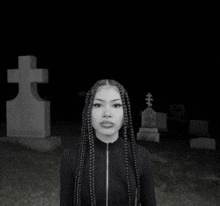 a black and white photo of a woman in a cemetery with a cross in the background