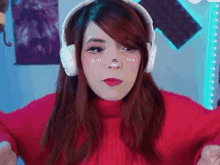 a woman wearing headphones and a red sweater is looking at the camera .