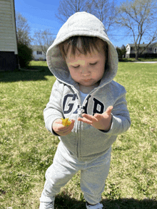 a baby wearing a gap hoodie is holding a flower