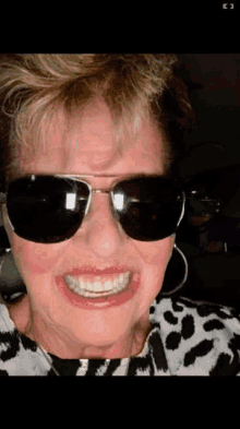 a woman wearing sunglasses is smiling and making a face