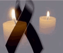 two lit candles with a black ribbon in the middle .