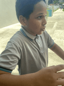 a young boy wearing a grey polo shirt looks to his left