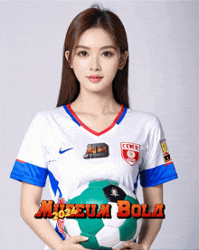 a woman in a museum bola jersey holds a soccer ball in her hands