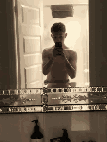 a man taking a picture of himself in a bathroom mirror with a shaving cream dispenser