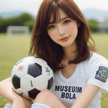 a woman holding a soccer ball wearing a museum bola shirt