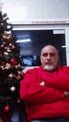 a man in a red jacket stands in front of a christmas tree with a sign that says apollo