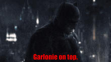 a picture of batman in the rain with the words garlonie on top above him