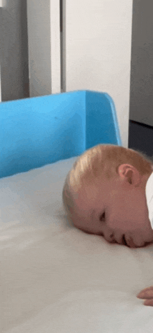 a baby is laying on a crib with his head on the mattress .