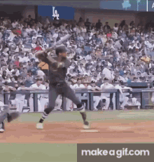 a baseball player is swinging a bat at a ball in front of a crowd at a baseball game .