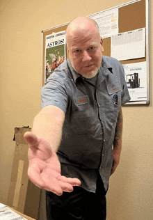 a man reaches out his hand in front of a bulletin board that says astros