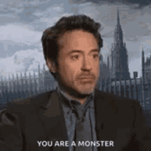 robert downey jr. is wearing a suit and tie and talking to someone .