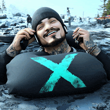 a man wearing headphones is laying on a black pillow with a blue x on it