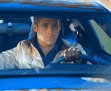 a man in a white jacket is driving a blue vehicle