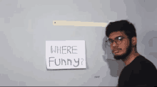 a man wearing glasses stands in front of a sign that says where funny