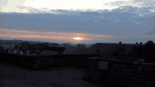 a sunset over a city with a stone wall in the foreground and a sign that says vendredi