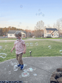 a young boy is playing with soap bubbles on the sidewalk