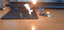 a lego figure is laying on a table with a laptop in the background