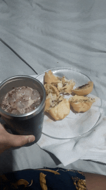 a person is holding a cup of iced chocolate next to a plate of food