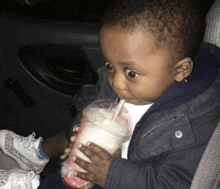 a little boy is drinking a milkshake with a straw