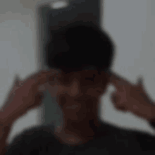 a blurry image of a man covering his ears with his hands .