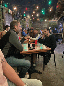 a group of people are sitting at a table with a sign that says exit on it