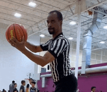 a referee is holding a wilson basketball in his hands