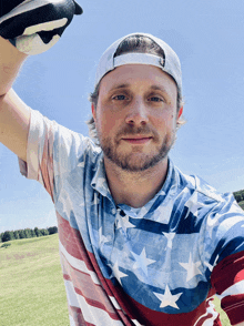 a man wearing a patriotic shirt is holding a golf ball