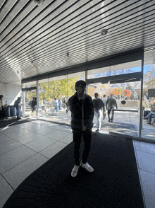 a man stands in front of a sliding glass door with people walking through it