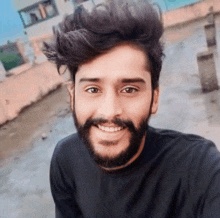 a man with a beard and a black shirt smiles for the camera