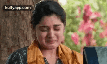 a woman is crying in front of a tree and flowers .