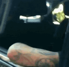 a man with a tattoo on his arm is sitting in a car .