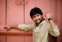 a man wearing a watch is leaning against a red door