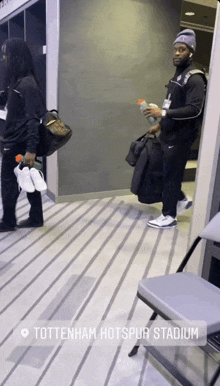 a picture of tottenham hotspur stadium shows a man carrying a bag