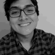 a man wearing glasses and a plaid shirt smiles