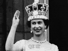 a black and white photo of queen elizabeth ii wearing a crown and waving .