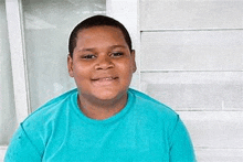 a young boy is wearing a blue shirt and smiling for the camera .