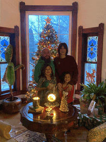 a family poses in front of a christmas tree in a living room