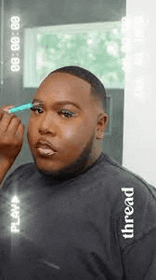 a man is applying makeup to his eyebrows .