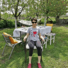 a woman wearing sunglasses is sitting in a chair in front of a table