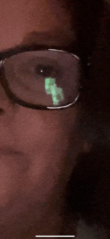 a close up of a person wearing glasses with a green reflection in the lenses