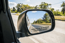 a car 's rear view mirror has a sticker on it that says limehalla is closer than you think