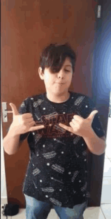 a young boy wearing a star wars t-shirt is standing in front of a door .