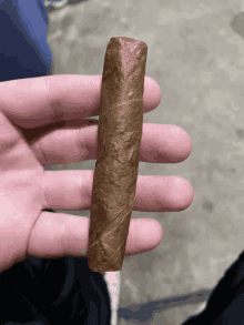 a person is holding a cigar in their hand with their fingers