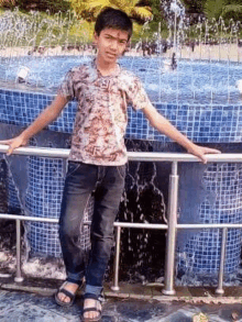 a young boy is standing next to a fountain in a park .