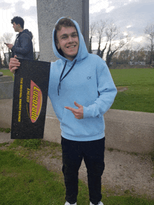 a man in a blue hoodie is holding a lubricants door mat