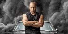 a bald man is standing in front of a black car with his arms crossed .