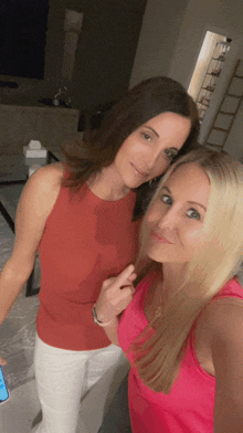 two women are posing for a picture and one is wearing a red tank top